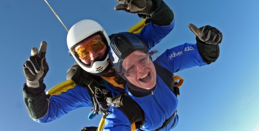 Two people in blue jumpsuits in the sky doing a skydive