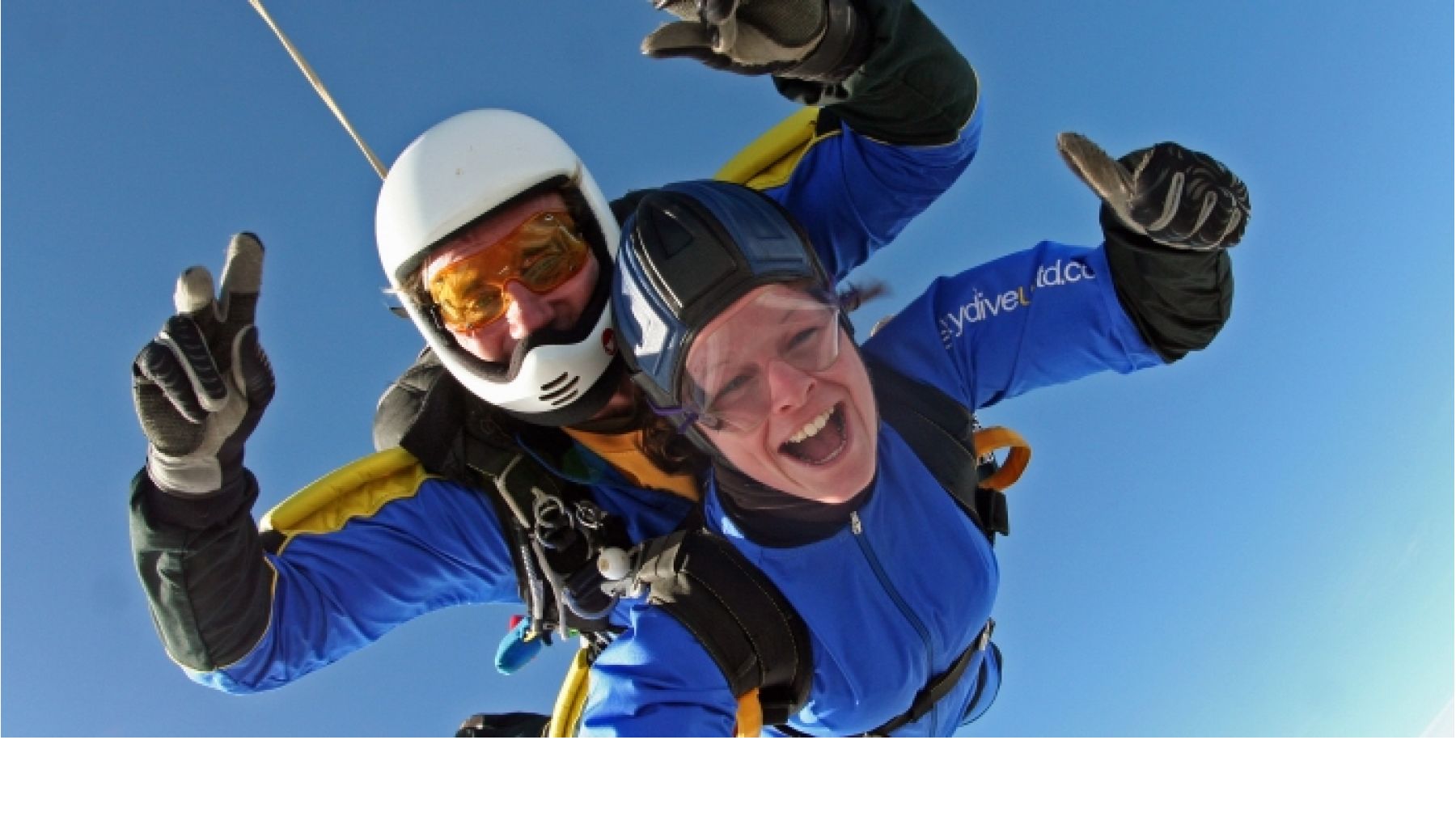 Two people in blue jumpsuits in the sky doing a skydive