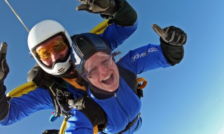 Two people in blue jumpsuits in the sky doing a skydive